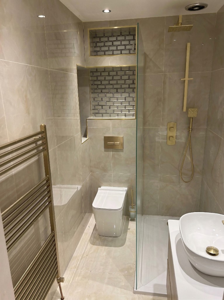Luxury bathroom — brass fixtures, marble-effect tiling and frameless shower