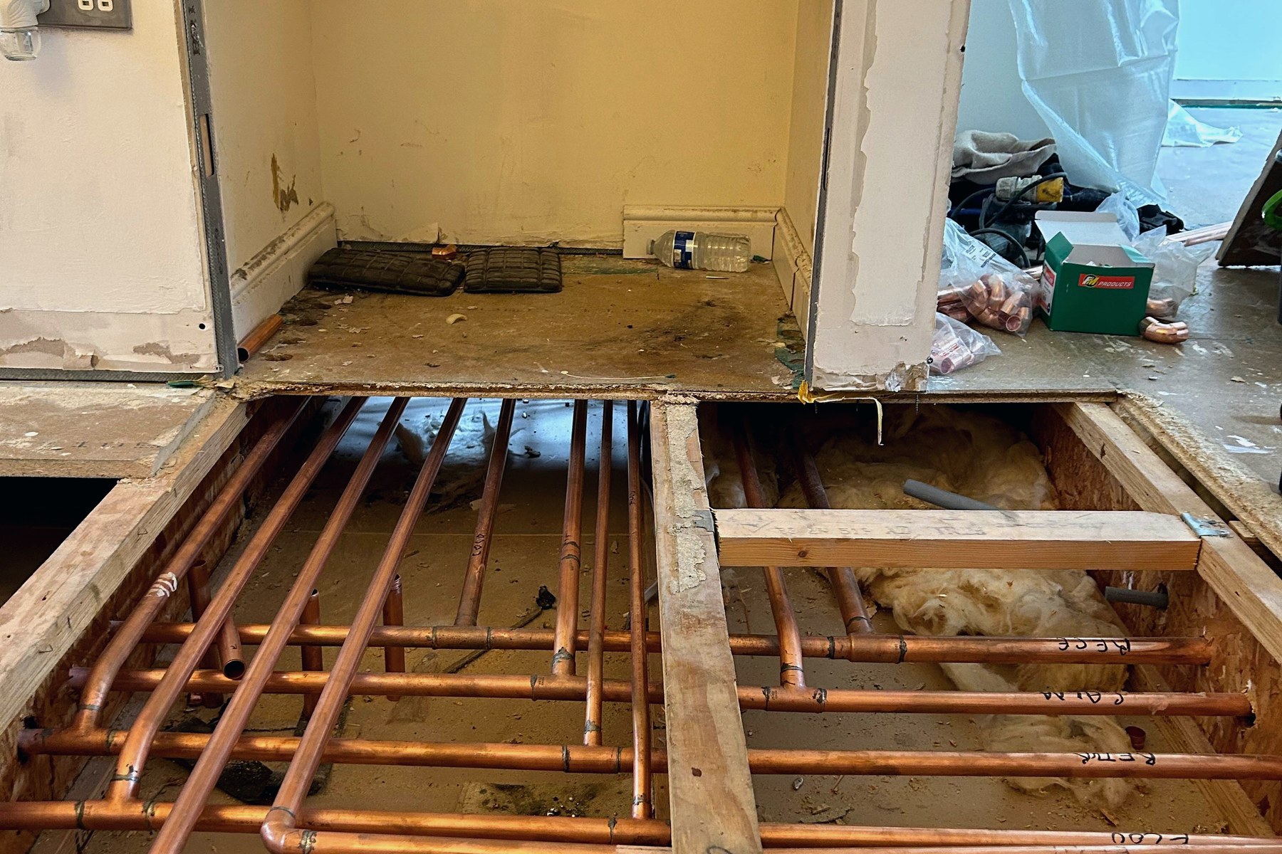 Labelled copper heating and underfloor pipework between joists
