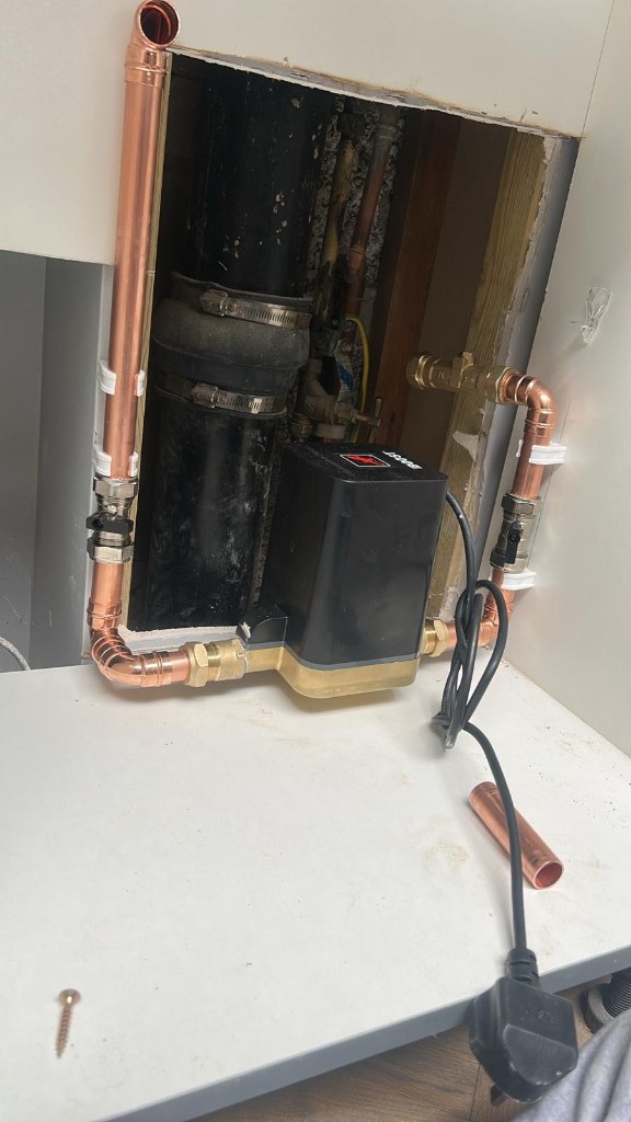 Water pressure boosting pump installed in a utility cupboard with new copper pipework and isolating valves